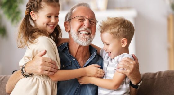 Grandfather hugging his grandchildren at home